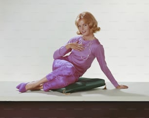 a woman in a purple dress sitting on a green cushion