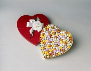 a heart shaped box of candy next to a heart shaped box of candy
