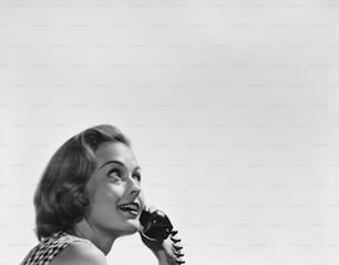 a black and white photo of a woman talking on a phone