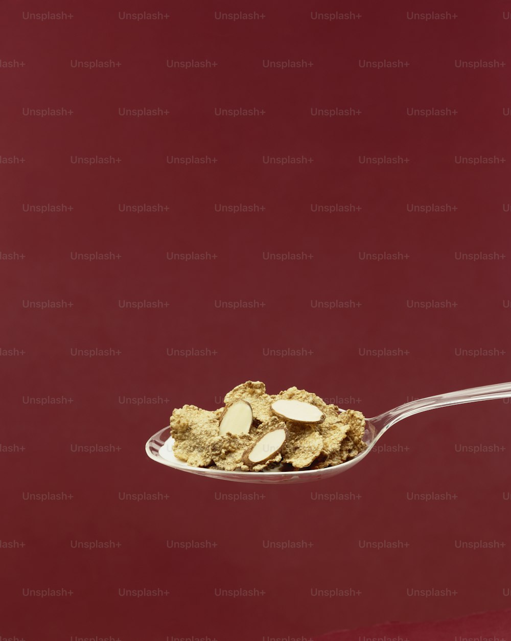 a spoon full of almonds on a red background