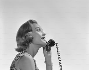 a woman talking on a telephone while wearing a dress