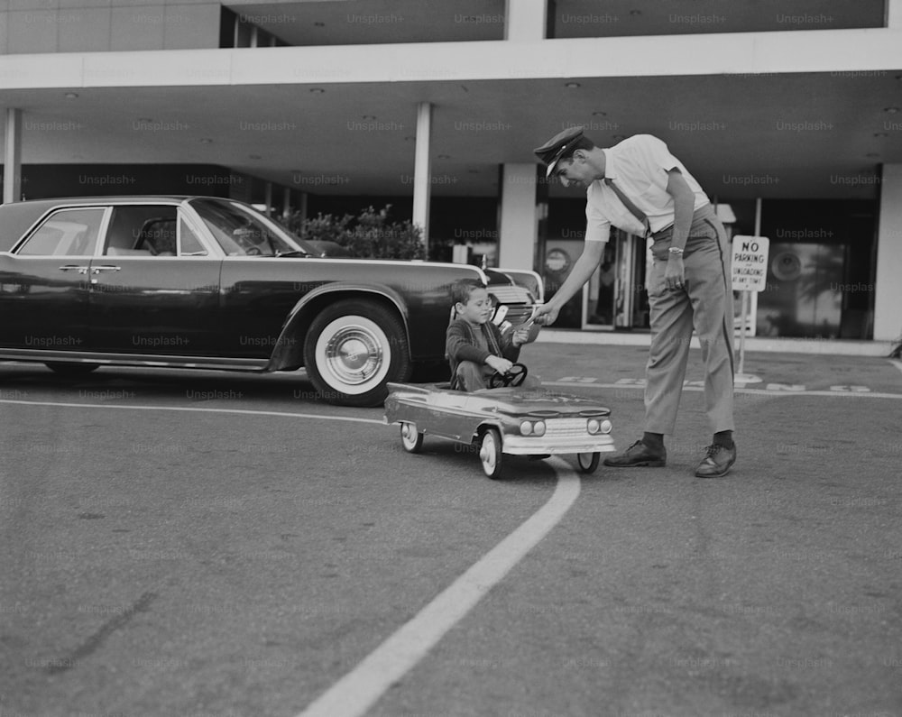 a black and white photo of a man pushing a child in a suitcase
