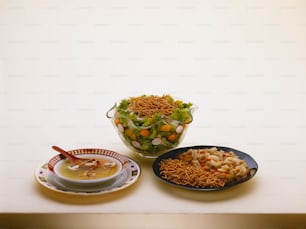 un plato de sopa, un tazón de fideos y un tazón de ensalada