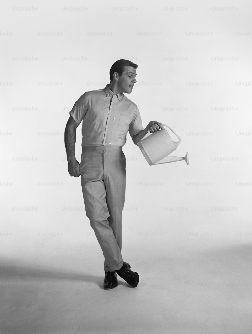 a man holding a bucket of water while standing in front of a white background