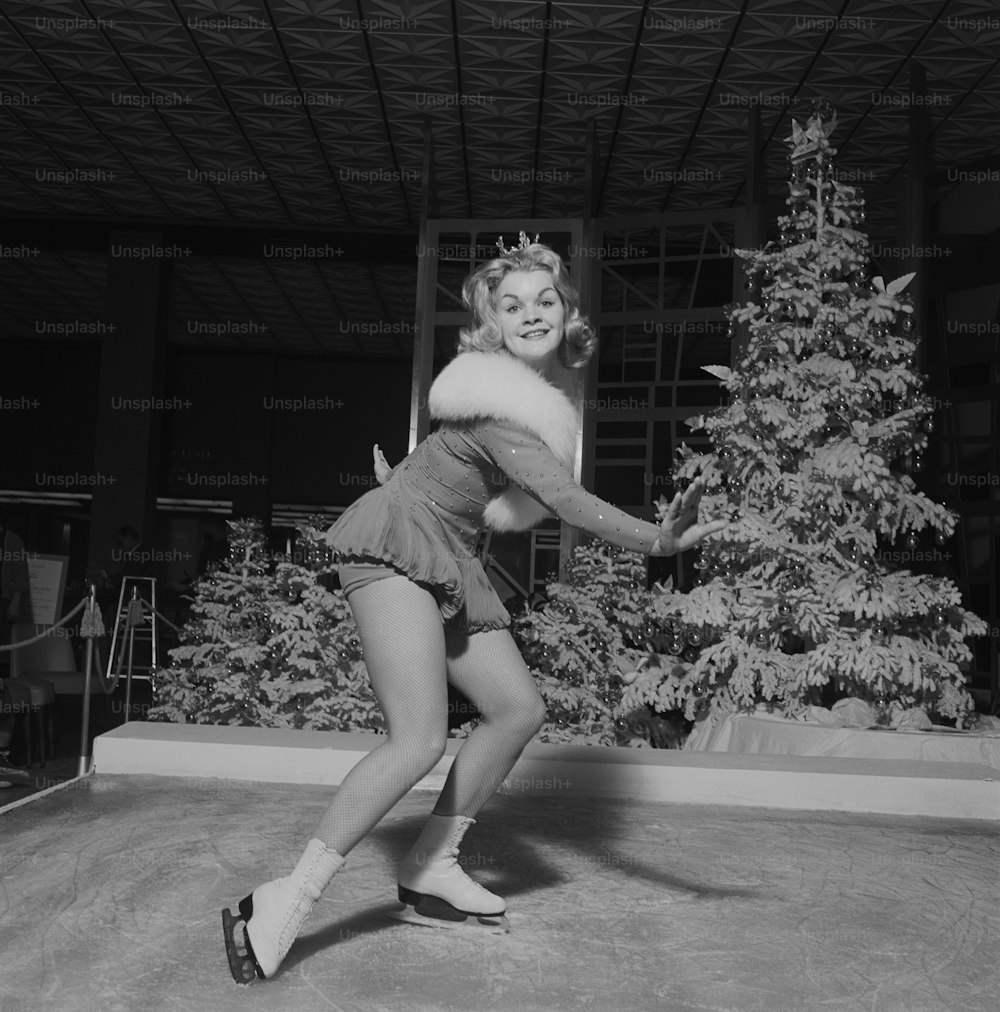 a black and white photo of a woman in front of a christmas tree