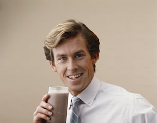 Un uomo in cravatta che tiene un bicchiere di latte