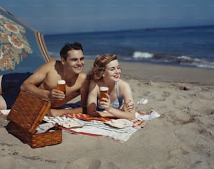 a man and a woman laying on a towel on the beach