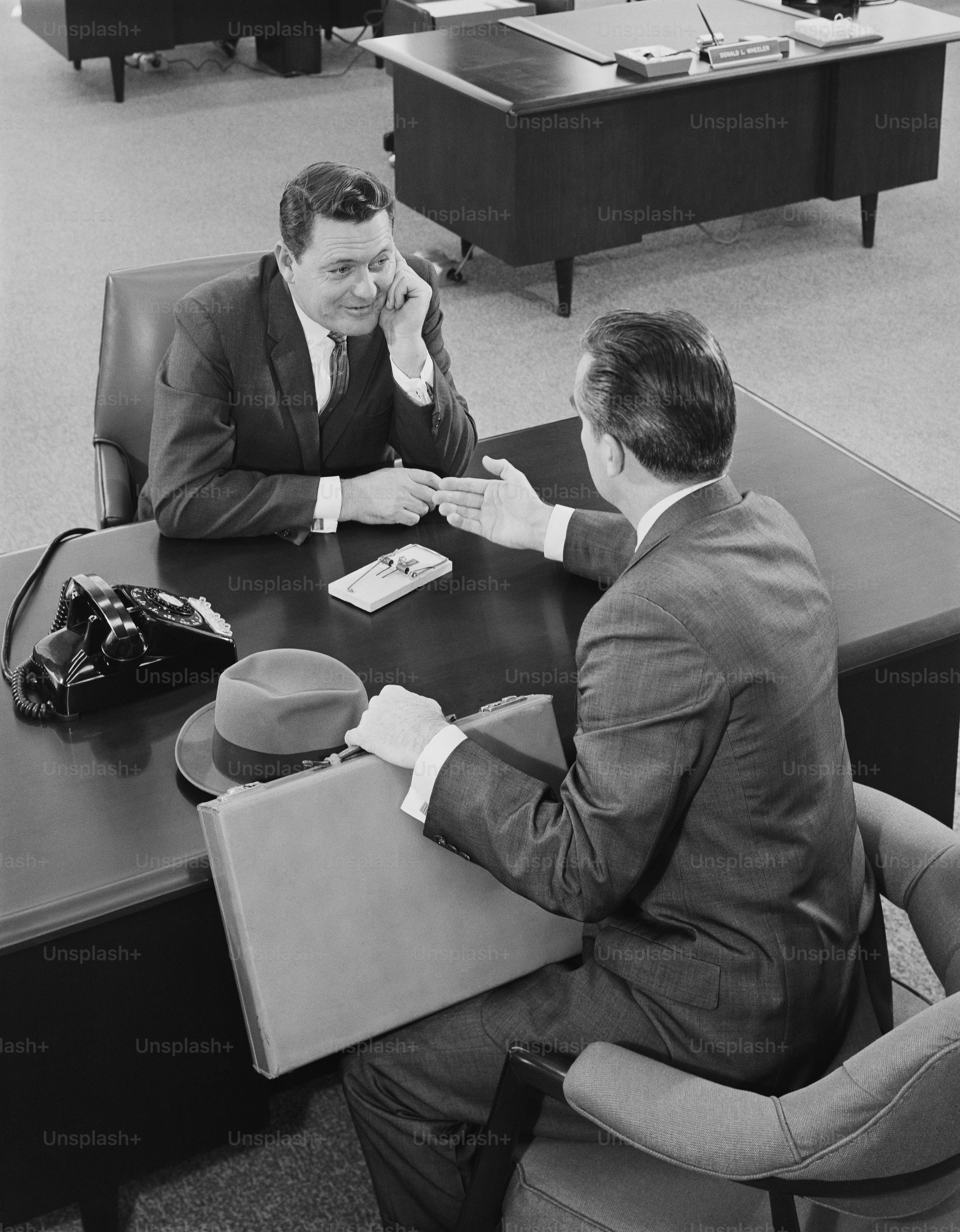 A black and white photo of three men sitting at a table photo – Office ...