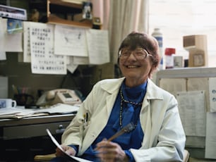 a woman sitting at a desk with a pen in her hand
