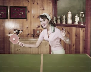 a woman holding a ping pong paddle in a room