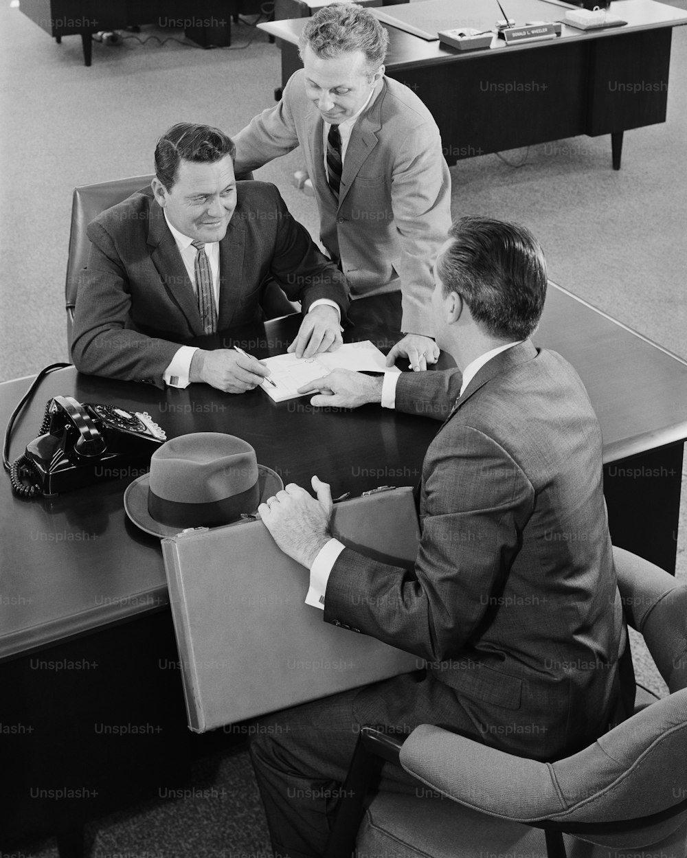 Ein Schwarz-Weiß-Foto von drei Männern, die an einem Tisch sitzen