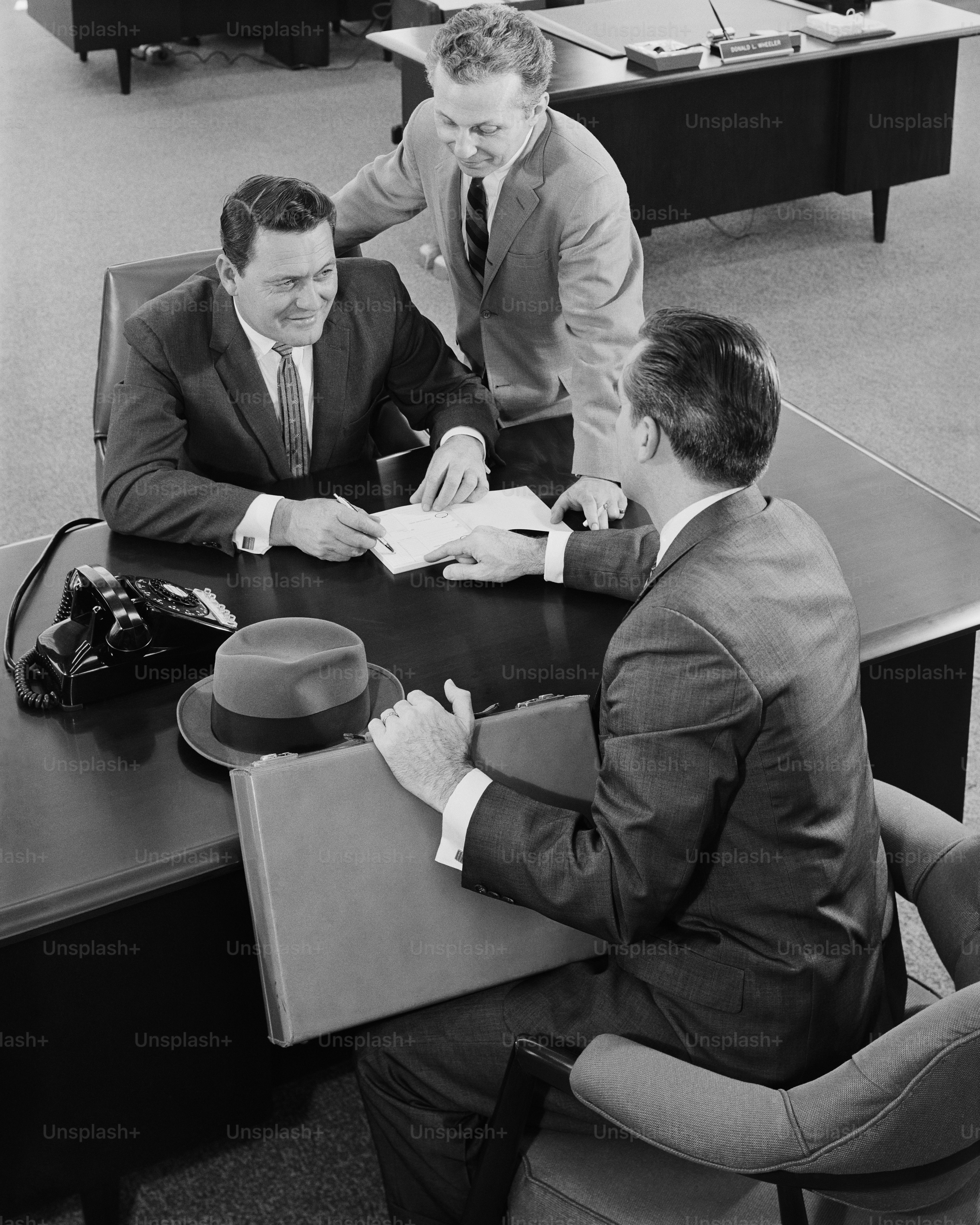 a black and white photo of three men sitting at a table