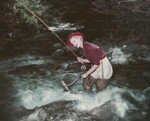 Un uomo in piedi in un fiume con una rete da pesca