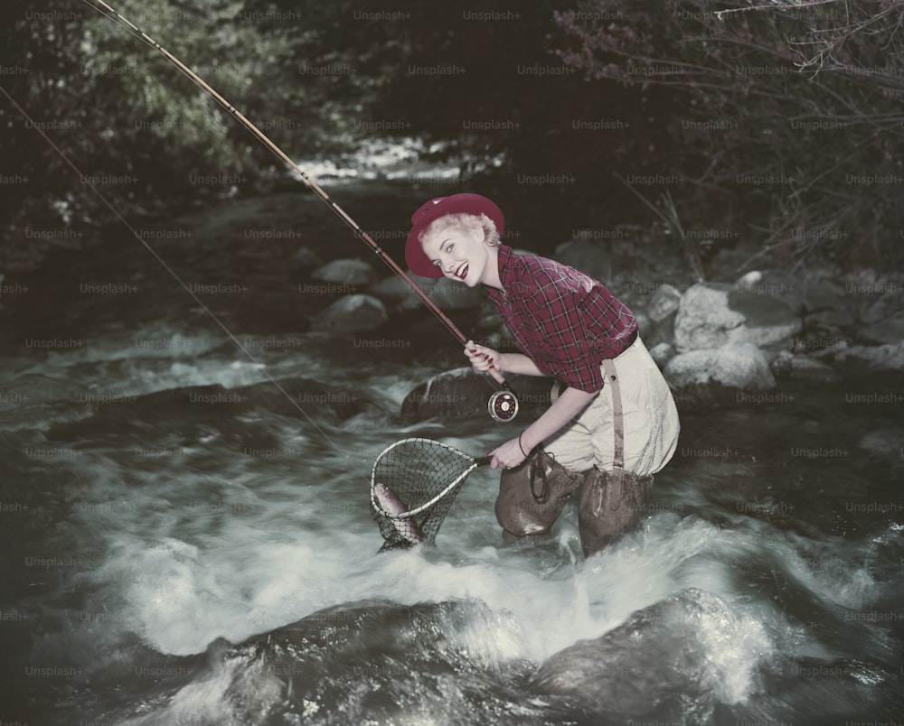 Un hombre parado en un río sosteniendo una red de pesca