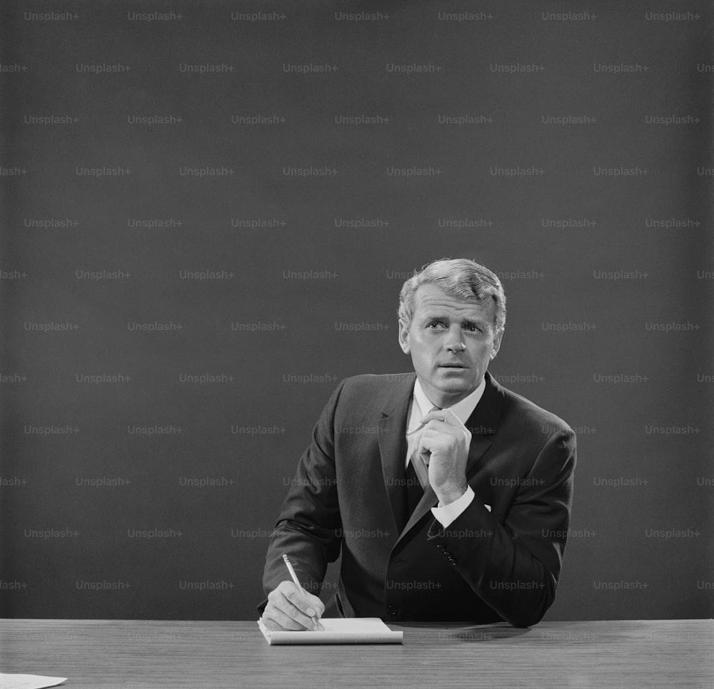 a black and white photo of a man sitting at a desk