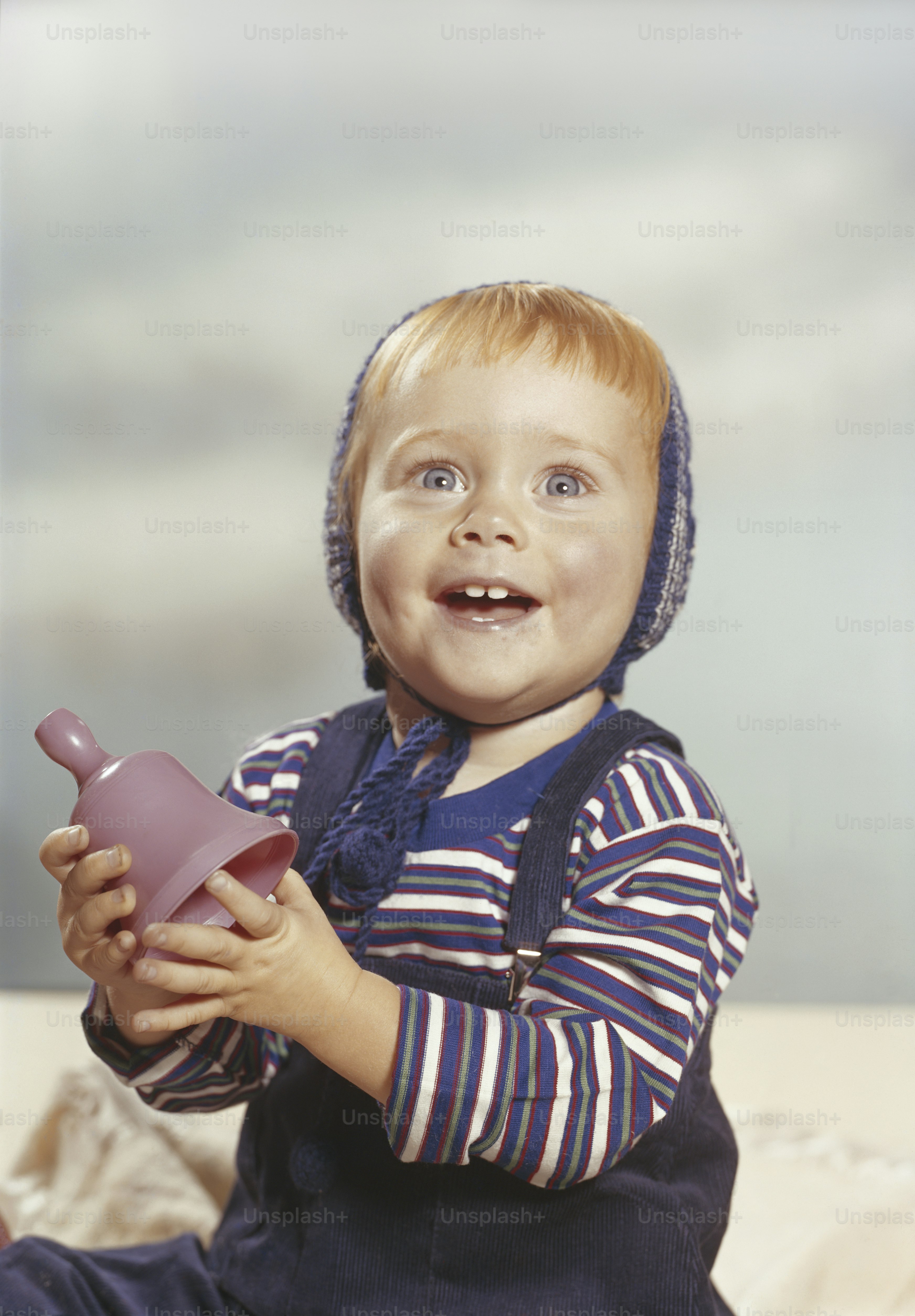 a little boy sitting on a bed holding a toy