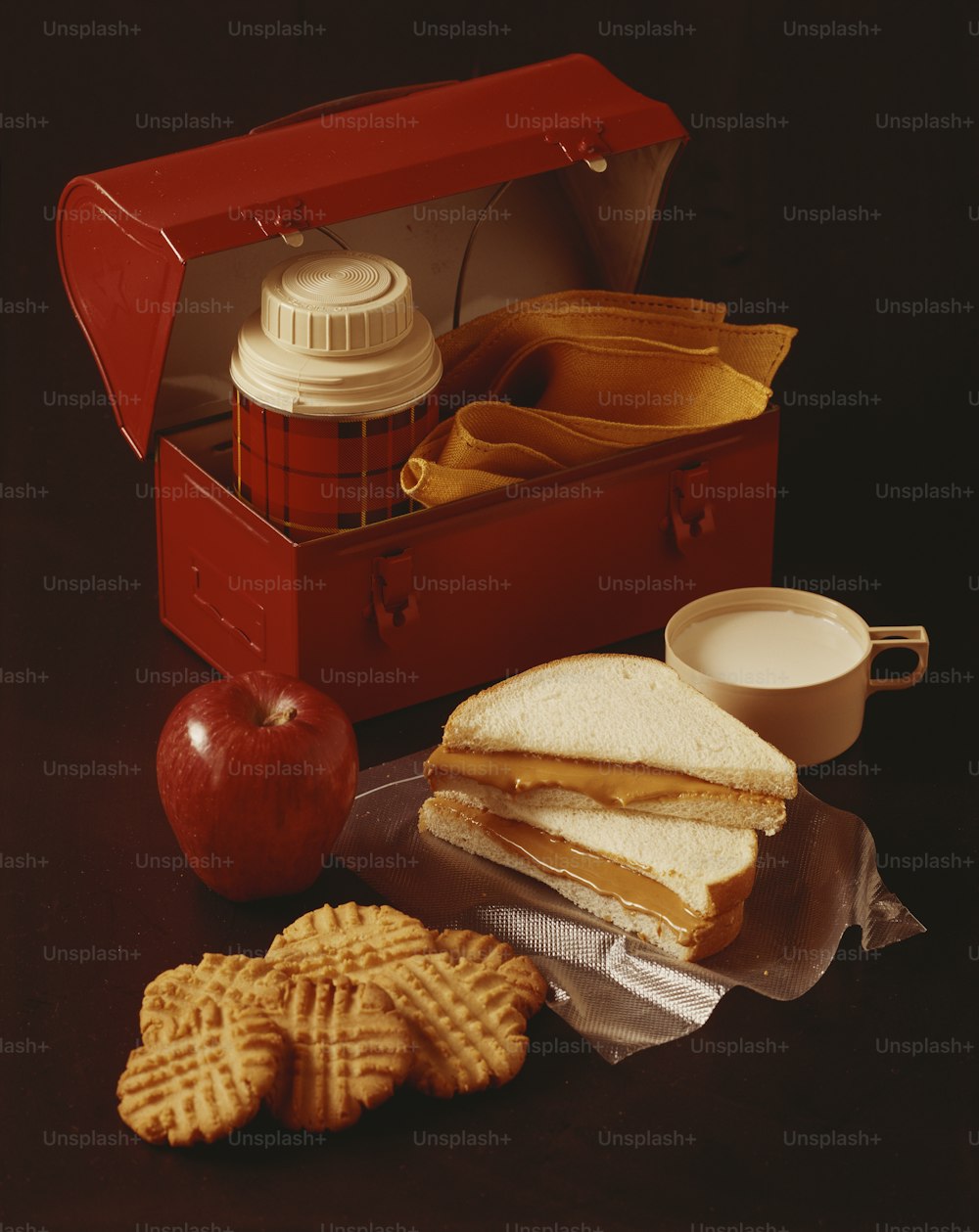 une boîte à lunch avec un sandwich, des craquelins et une pomme