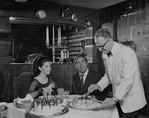 a black and white photo of a man cutting a cake