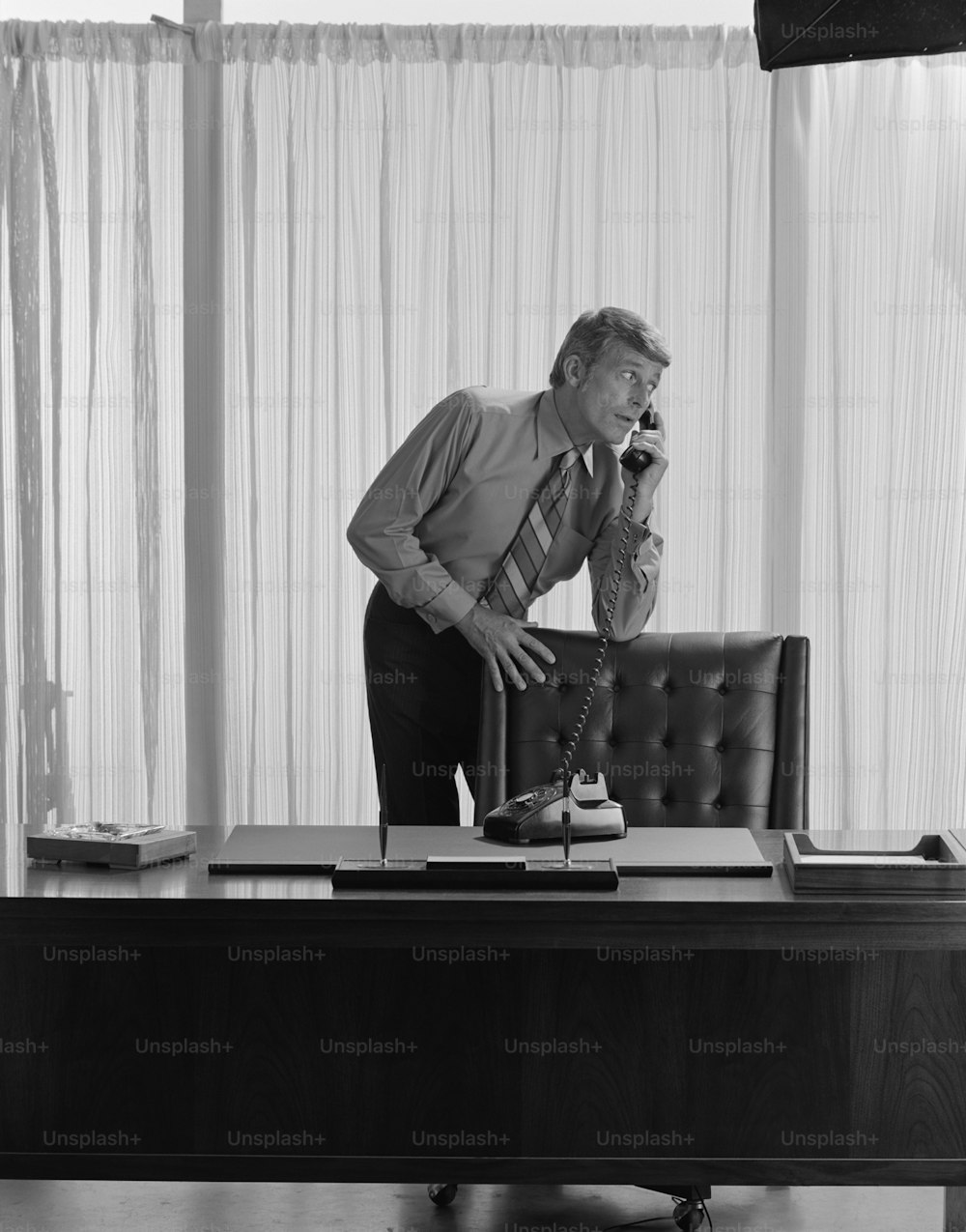 a man standing at a desk talking on a phone