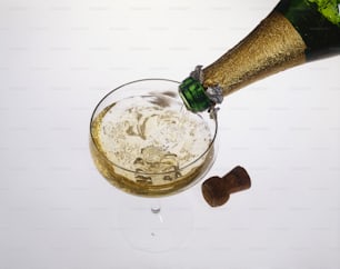 uma garrafa de champanhe sendo derramada em uma taça de vinho