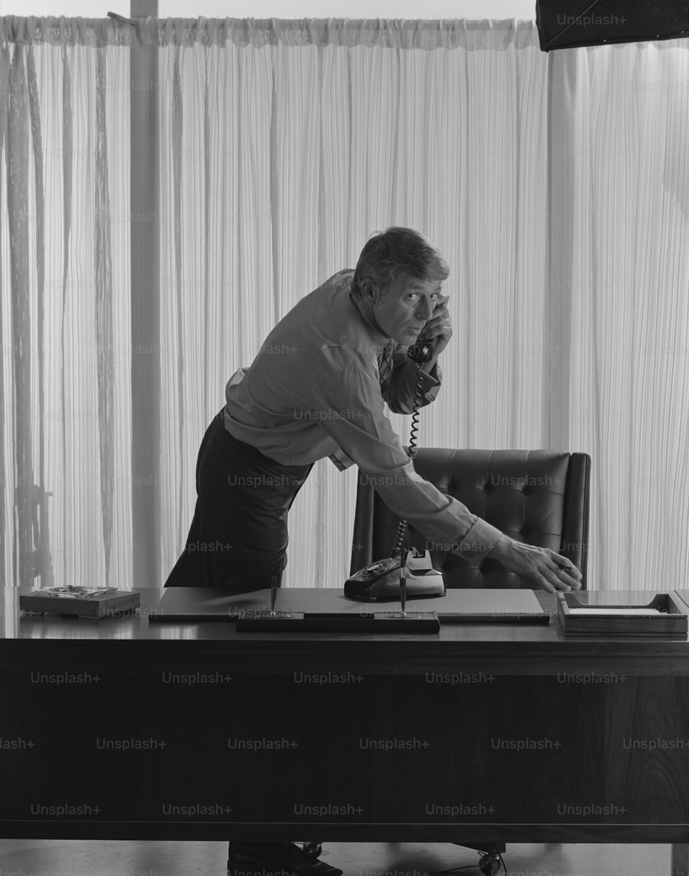 a man sitting at a desk talking on a phone