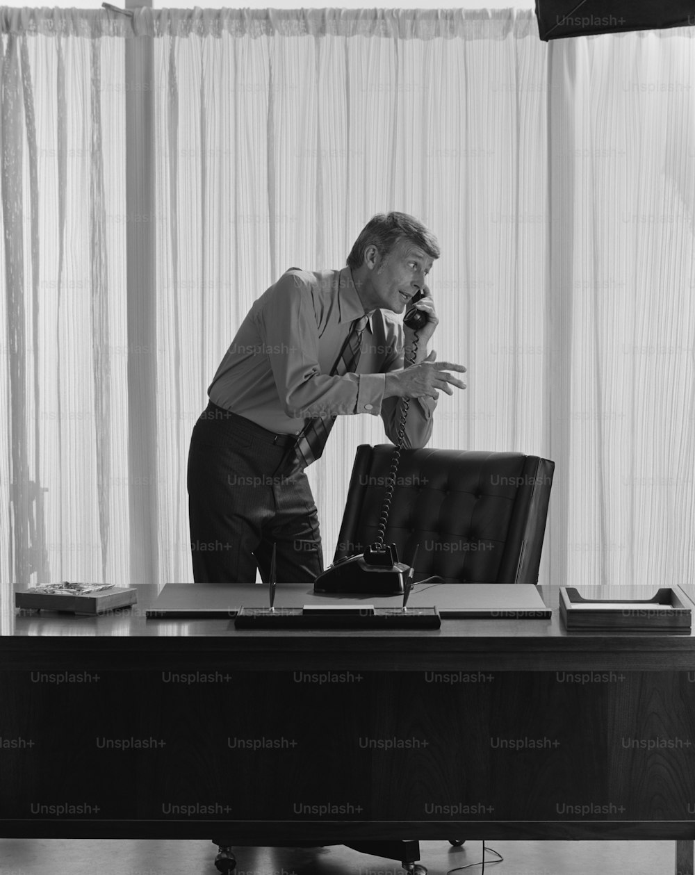 a man standing at a desk talking on a phone