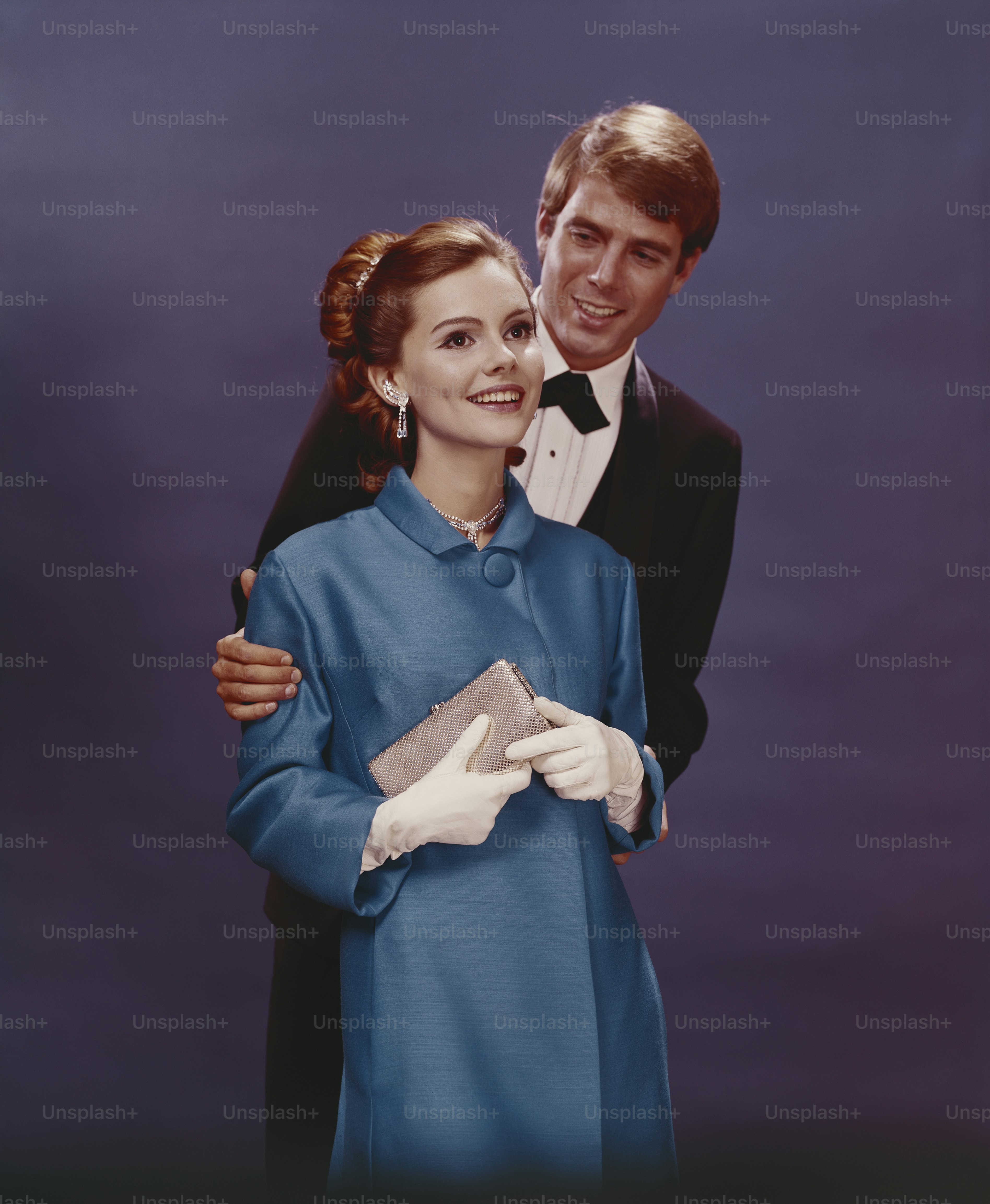 a man in a tuxedo standing next to a woman in a blue dress