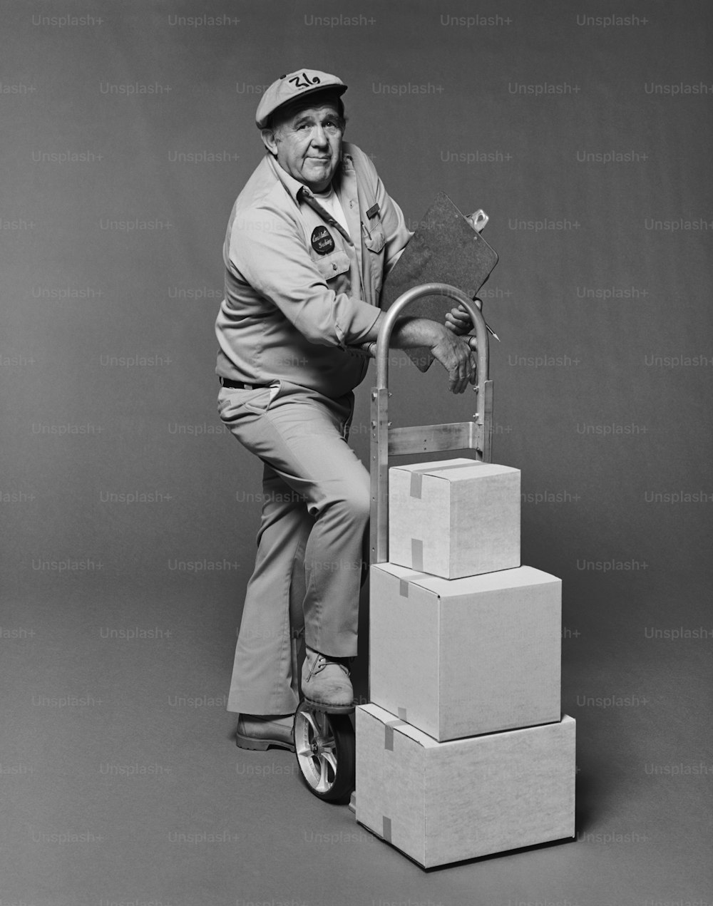 a black and white photo of a man leaning on a stack of boxes