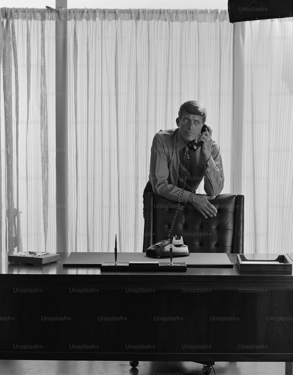 um homem sentado em uma mesa falando ao telefone