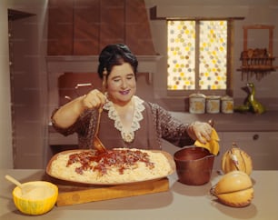 a woman is making a pizza in the kitchen