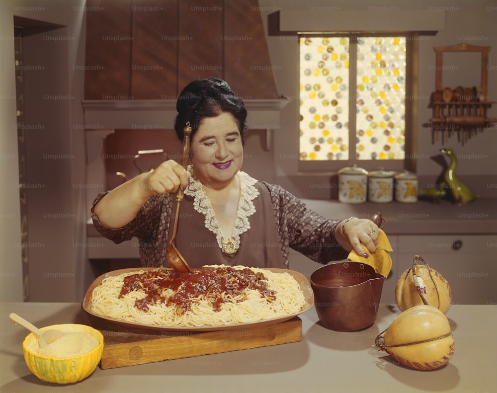 a woman is making a pizza in the kitchen