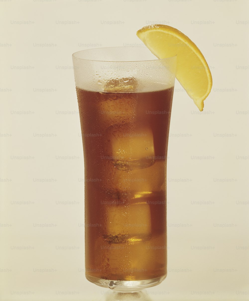 a tall glass filled with ice and a lemon wedge