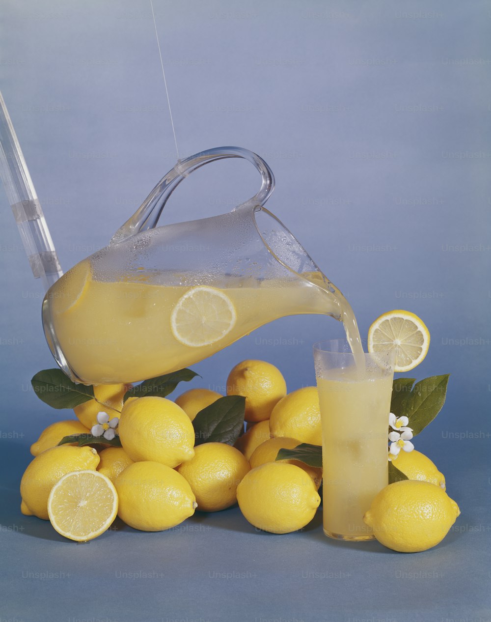 um jarro de limonada sendo derramado sobre uma pilha de limões