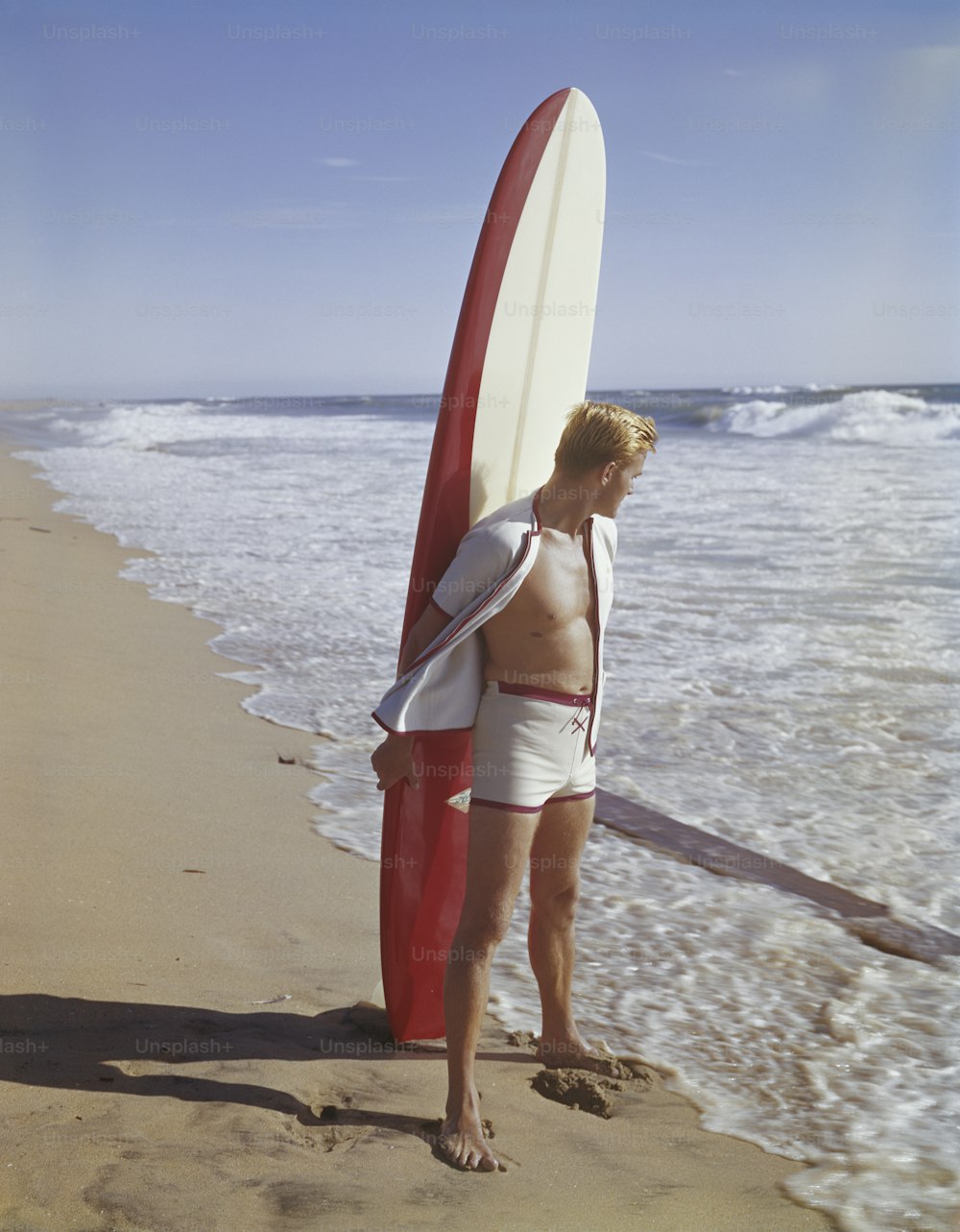 서핑보드를 들고 해변에 서 있는 남자