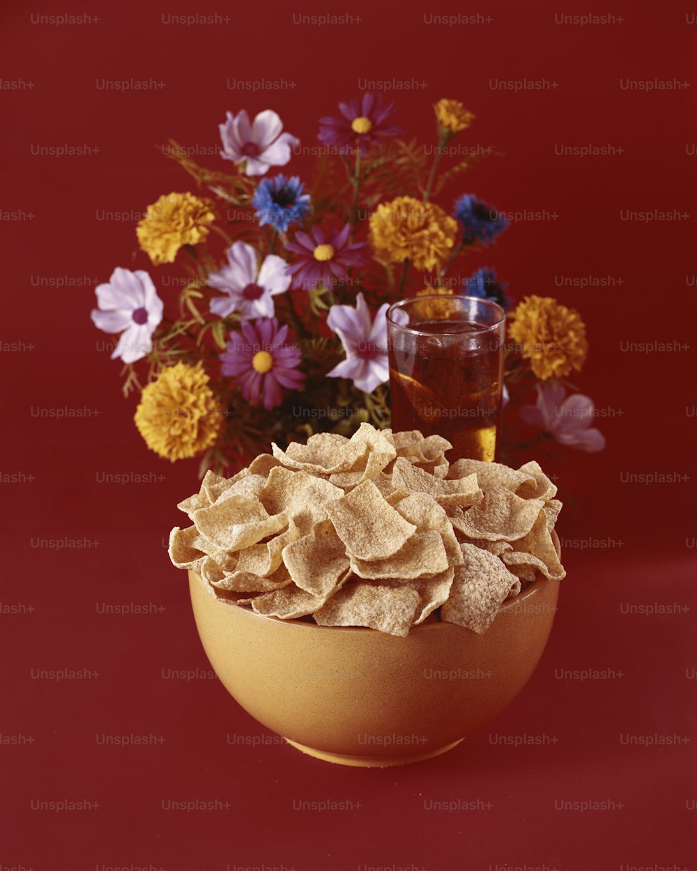 a bowl of chips next to a vase of flowers
