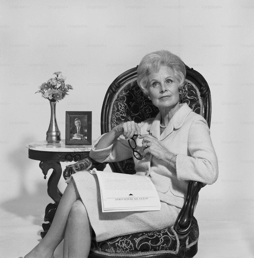a black and white photo of a woman sitting in a chair