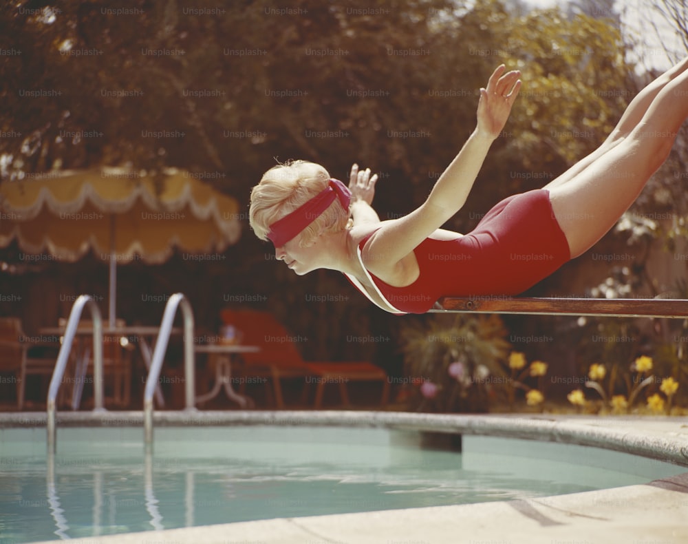 Eine Frau in einem roten Badeanzug taucht in einen Pool