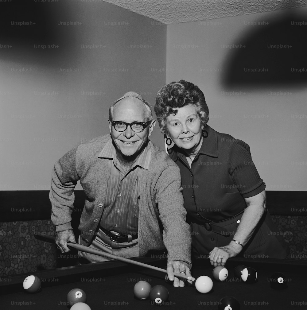 a man and a woman leaning over a pool table
