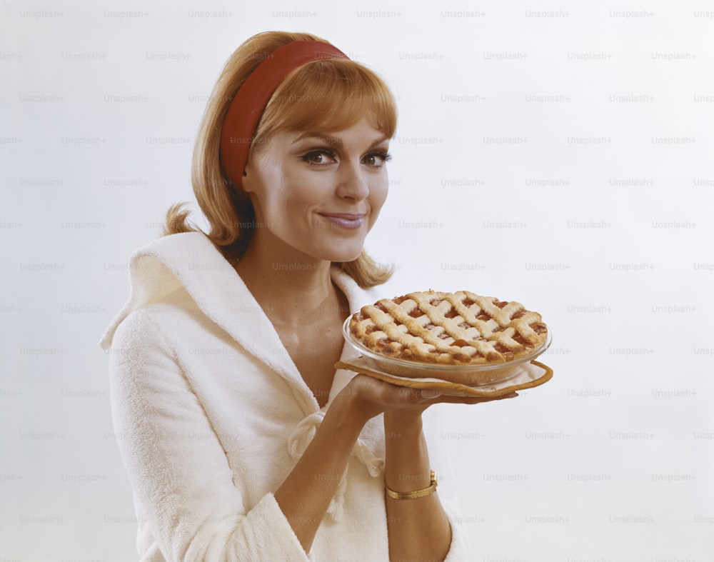 Una mujer sosteniendo un pastel en un plato