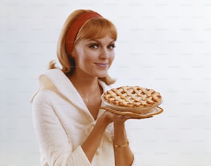 a woman holding a pie on a plate