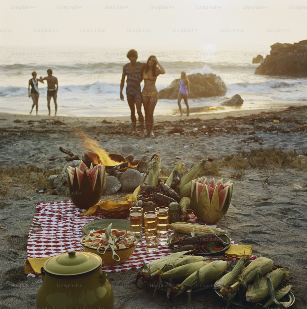 a group of people standing on top of a beach next to a fire