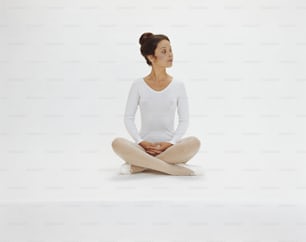 a woman sitting in a yoga position with her legs crossed