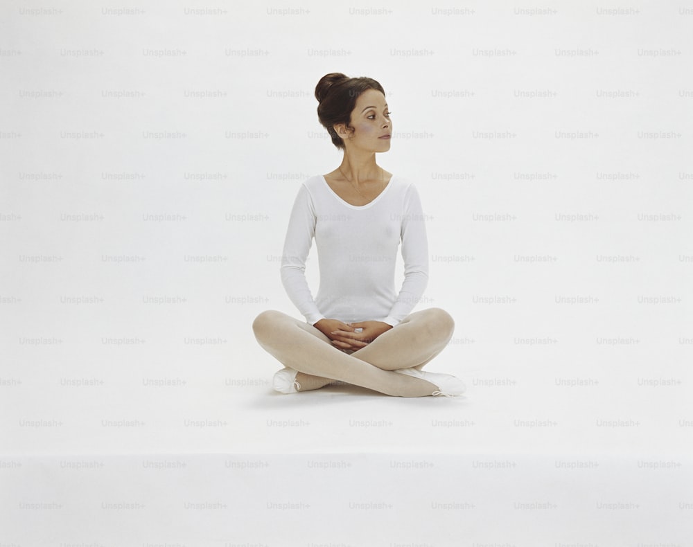 a woman sitting in a yoga position with her legs crossed