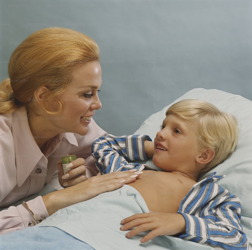 a woman laying in bed next to a little boy