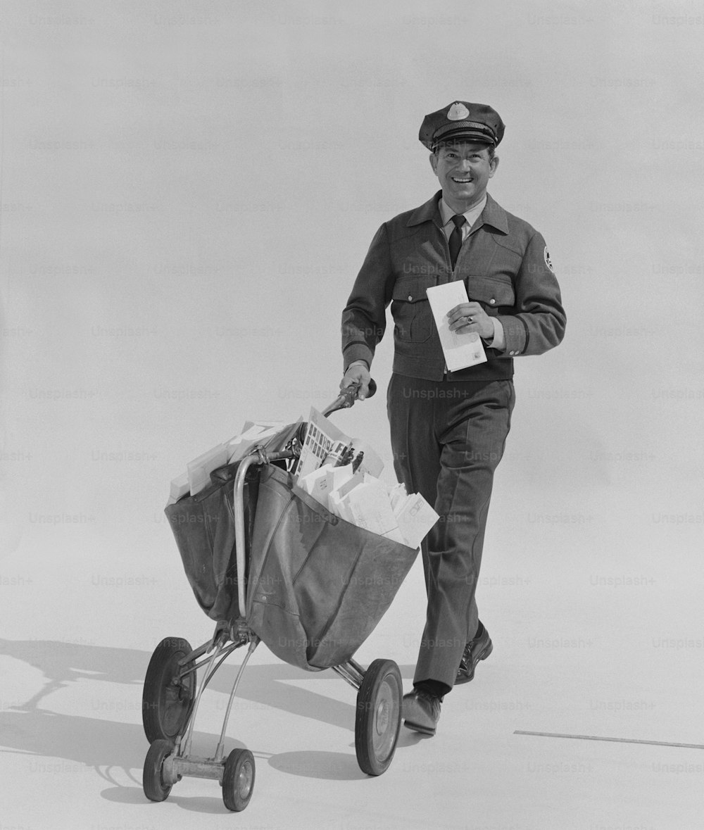 a black and white photo of a man in uniform pulling a wagon