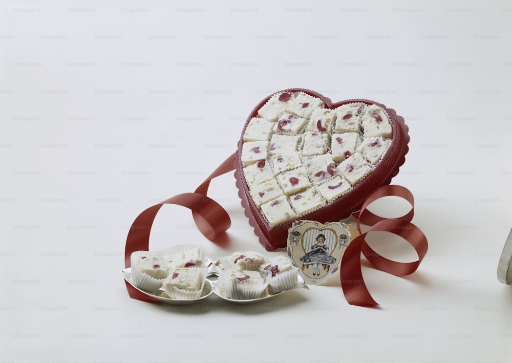 a heart shaped box of cookies next to a ribbon