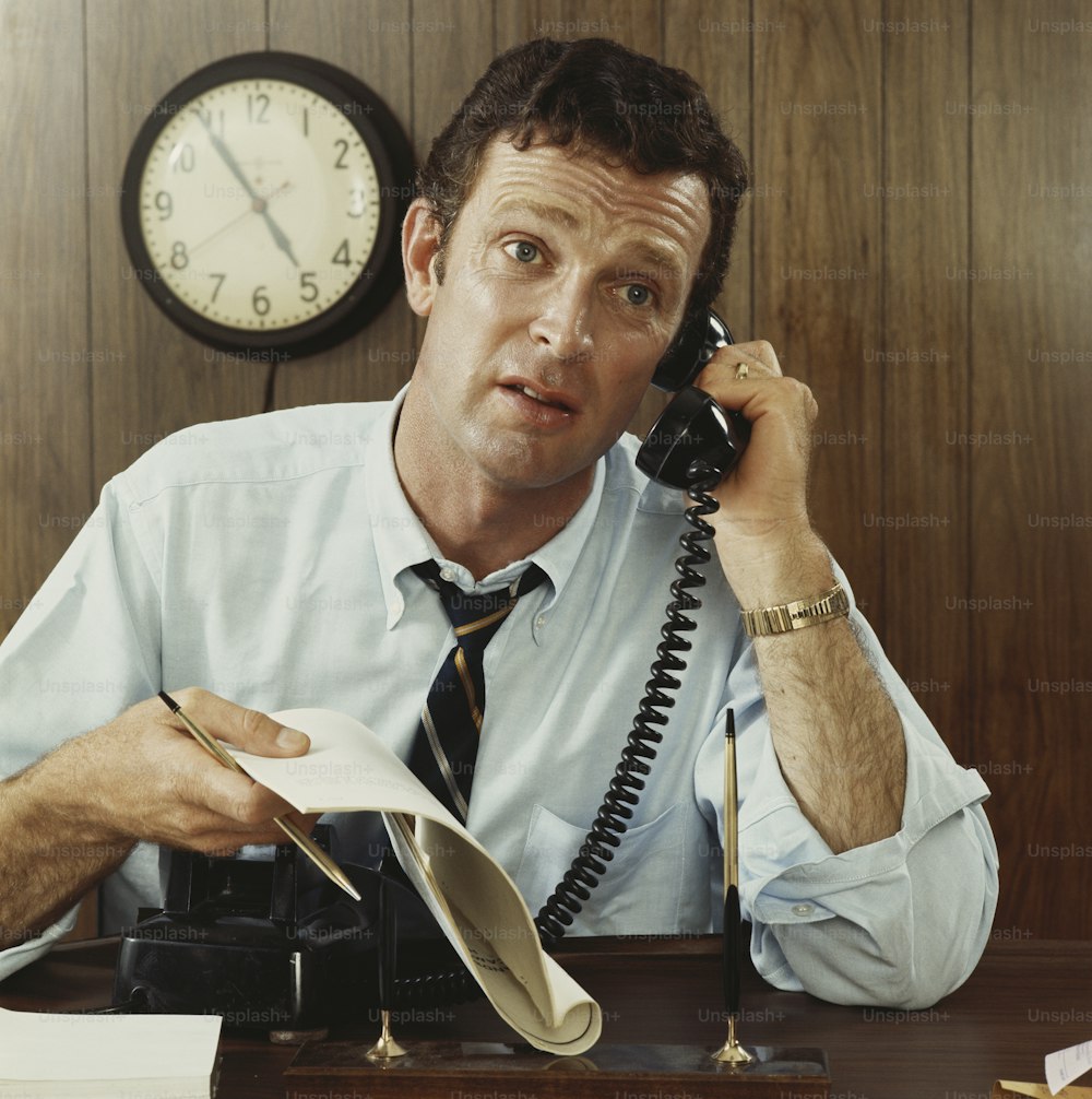 Un hombre sentado en un escritorio hablando por teléfono