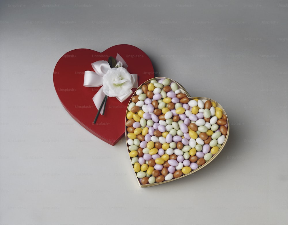 a heart shaped box filled with candy next to a heart shaped box with a flower