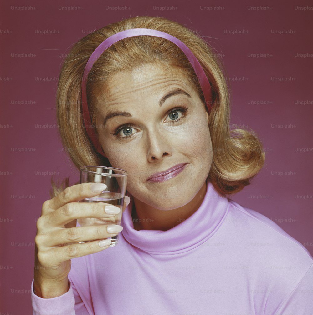 a woman in a pink shirt holding a glass of water