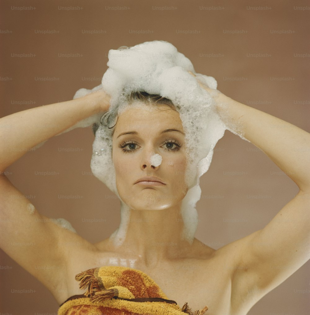 a woman with a towel on her head is washing her hair